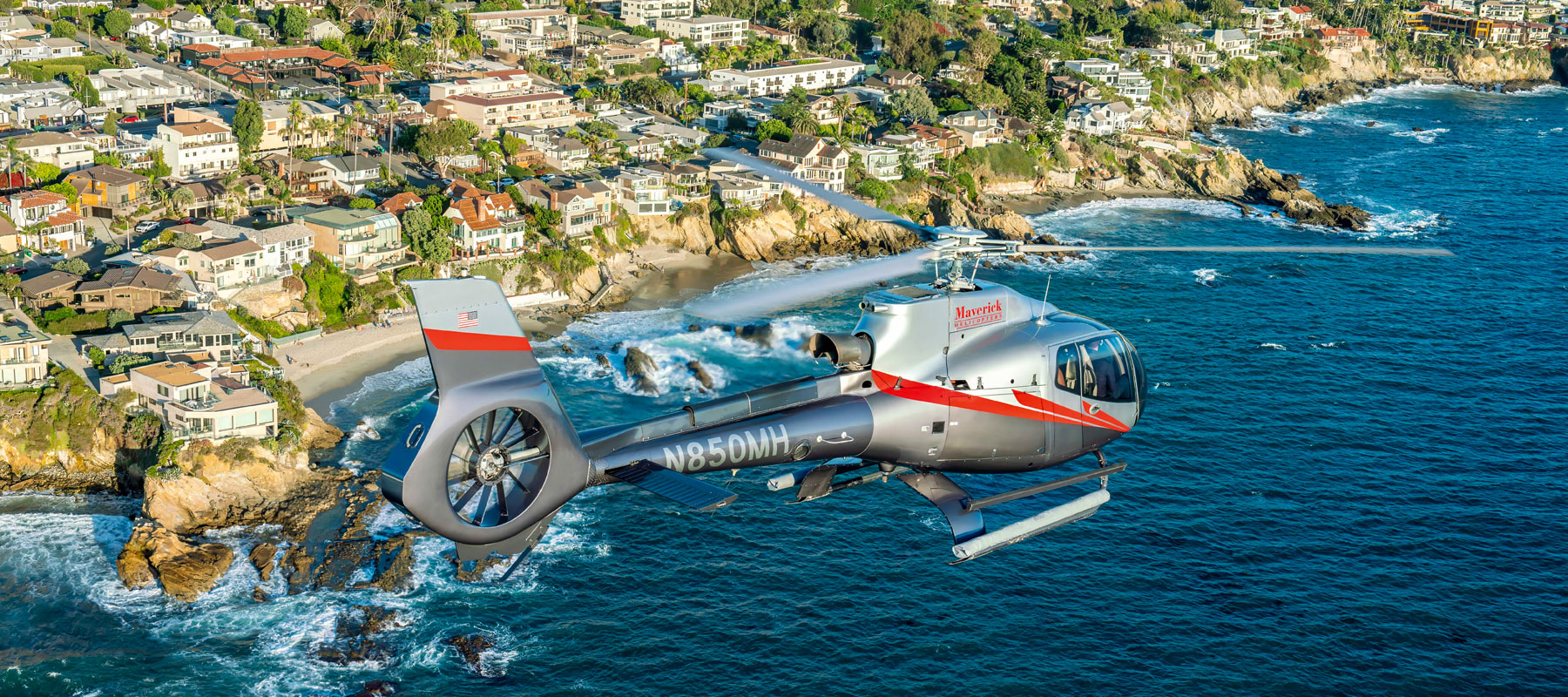 Helicopter flying over Laguna Beach's coastline and hillside homes