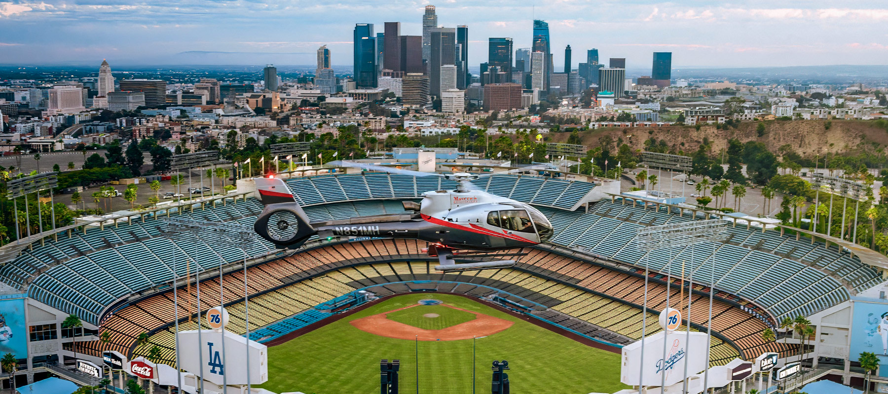 Maverick Helicopters aircraft above Dodger Stadium with the Los Angeles skyline in the background