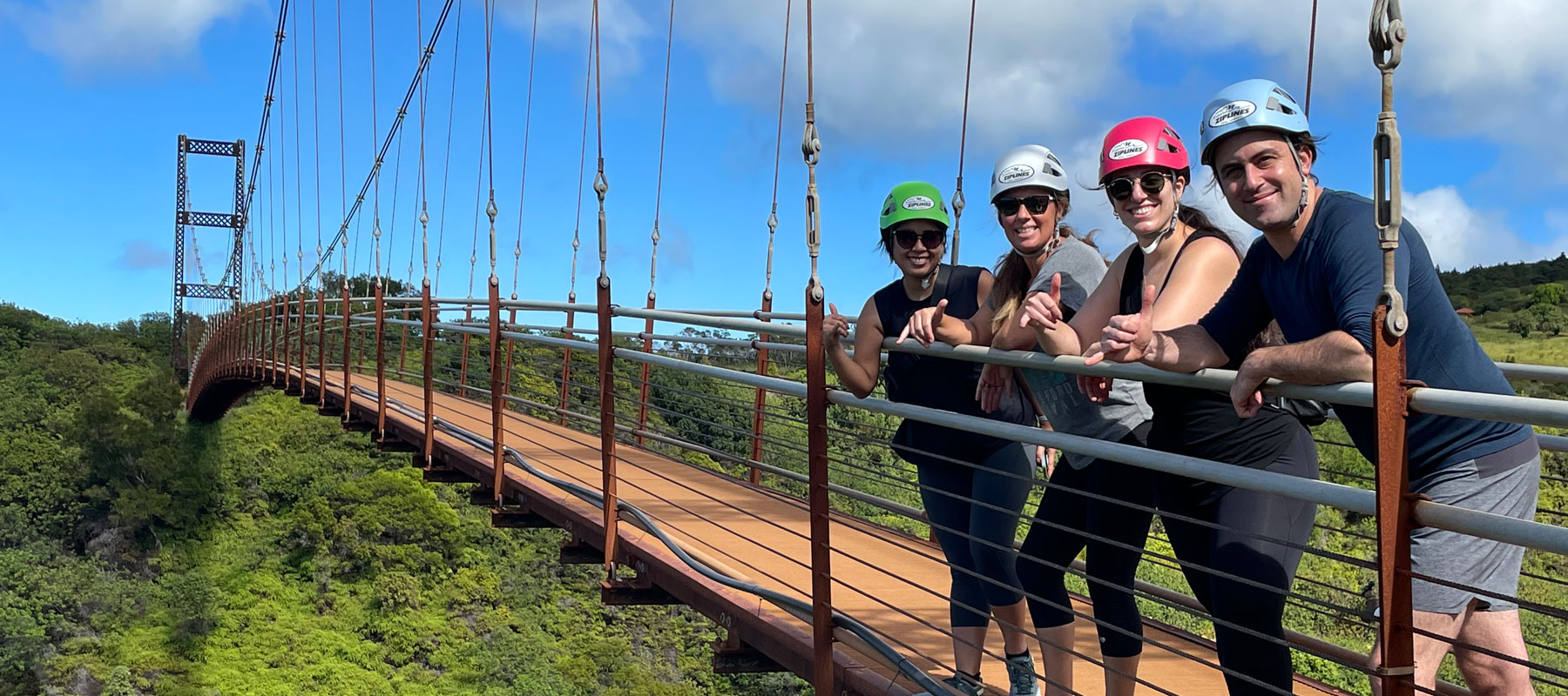 Guest in red ziplining with Pacific Ocean and Maui coastline in the background