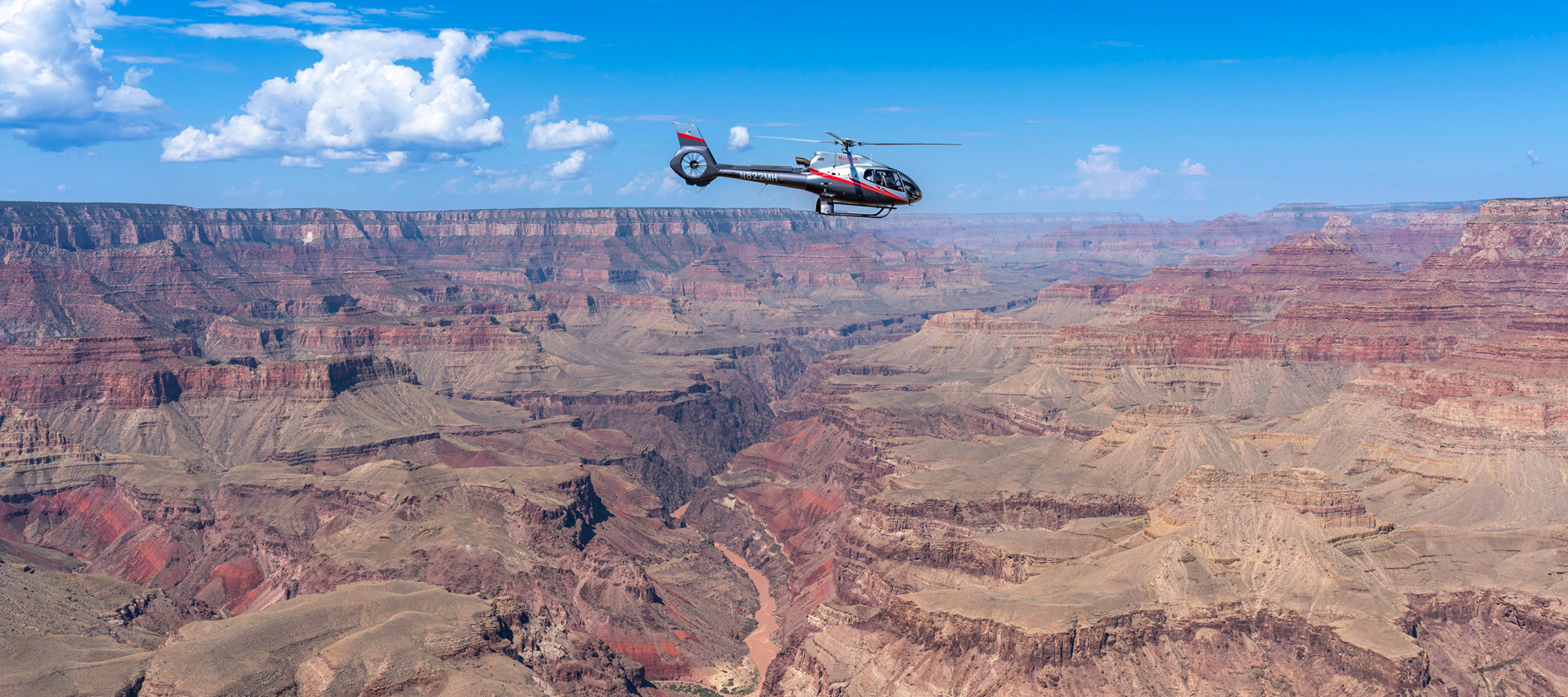 Maverick Helicopter flying above the colorful rock formations of the Grand Canyon South Rim