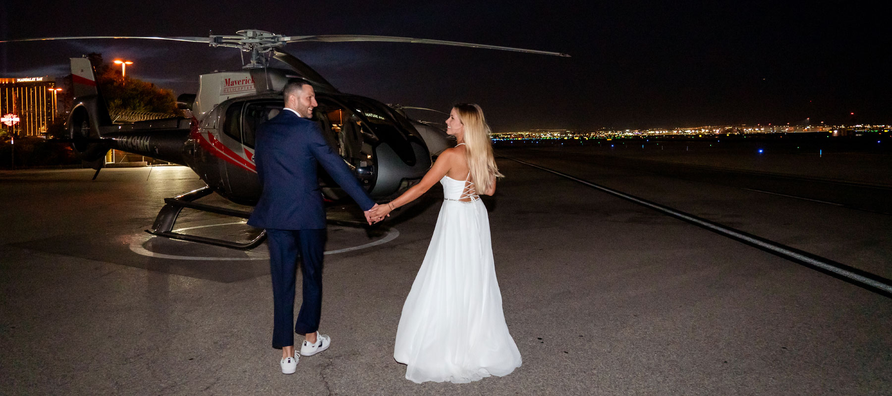 Bride and groom beneath the Las Vegas skyline after their neon lights helicopter wedding